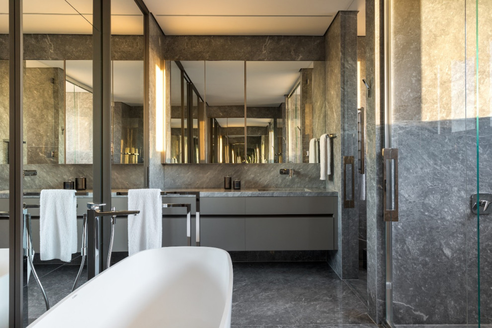 Inspiration for a contemporary bathroom in New York with flat-panel cabinets, grey cabinets, a freestanding tub, an alcove shower, an undermount sink, grey floor, a hinged shower door, grey benchtops, an enclosed toilet, a single vanity and a floating vanity.