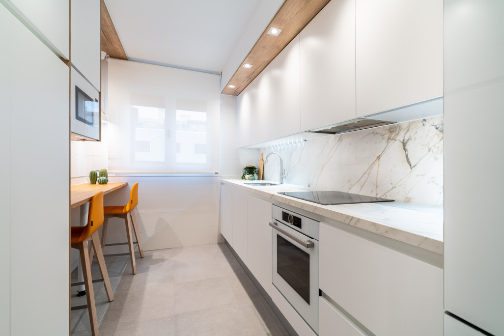 Photo of a small scandinavian galley enclosed kitchen in Other with a submerged sink, flat-panel cabinets, white cabinets, engineered stone countertops, white splashback, white appliances, ceramic flooring, no island, grey floors and white worktops.