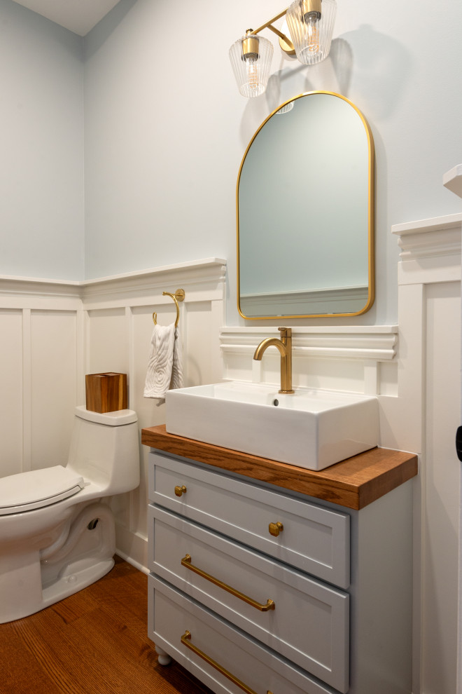 Powder room - medium tone wood floor powder room idea with blue cabinets, blue walls, wood countertops and a built-in vanity