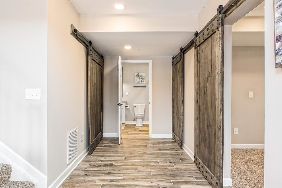This is an example of a large country hallway in Columbus with beige walls, porcelain floors and brown floor.