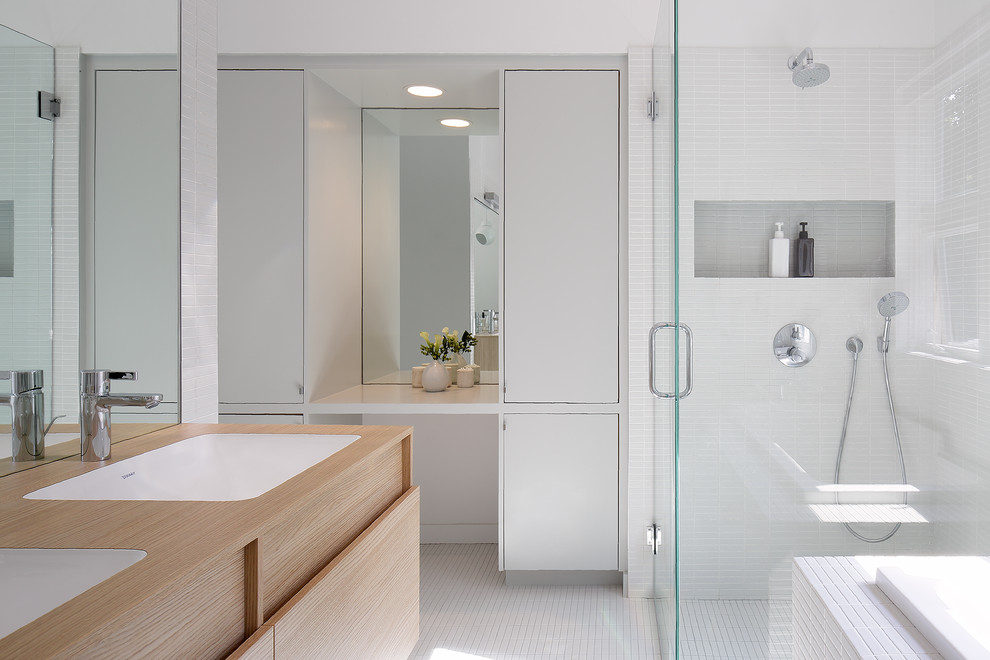 This is an example of a contemporary bathroom in New York with an undermount sink, flat-panel cabinets, light wood cabinets, a corner shower, white tile and mosaic tile floors.