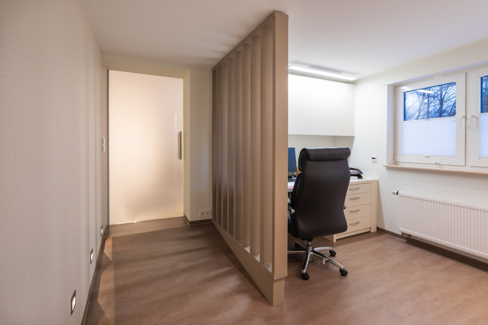 Aménagement d'un petit bureau moderne avec un sol en vinyl, un bureau intégré, un sol marron, un plafond décaissé et du papier peint.