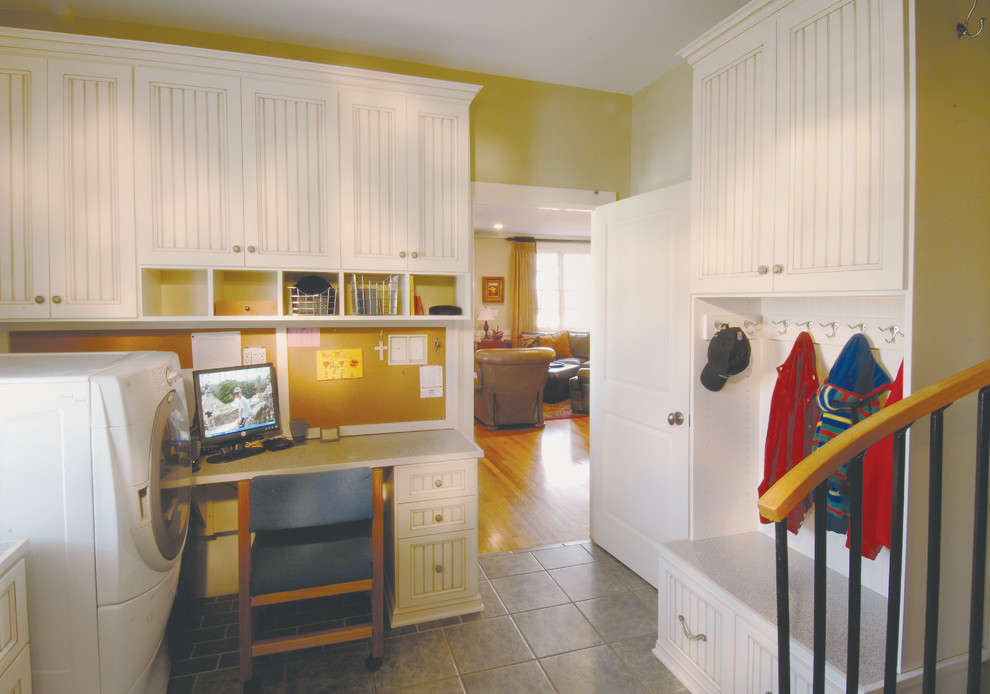 Inspiration for a mid-sized country l-shaped utility room in Philadelphia with shaker cabinets, white cabinets, yellow walls, ceramic floors, a side-by-side washer and dryer, quartz benchtops, grey floor and white benchtop.