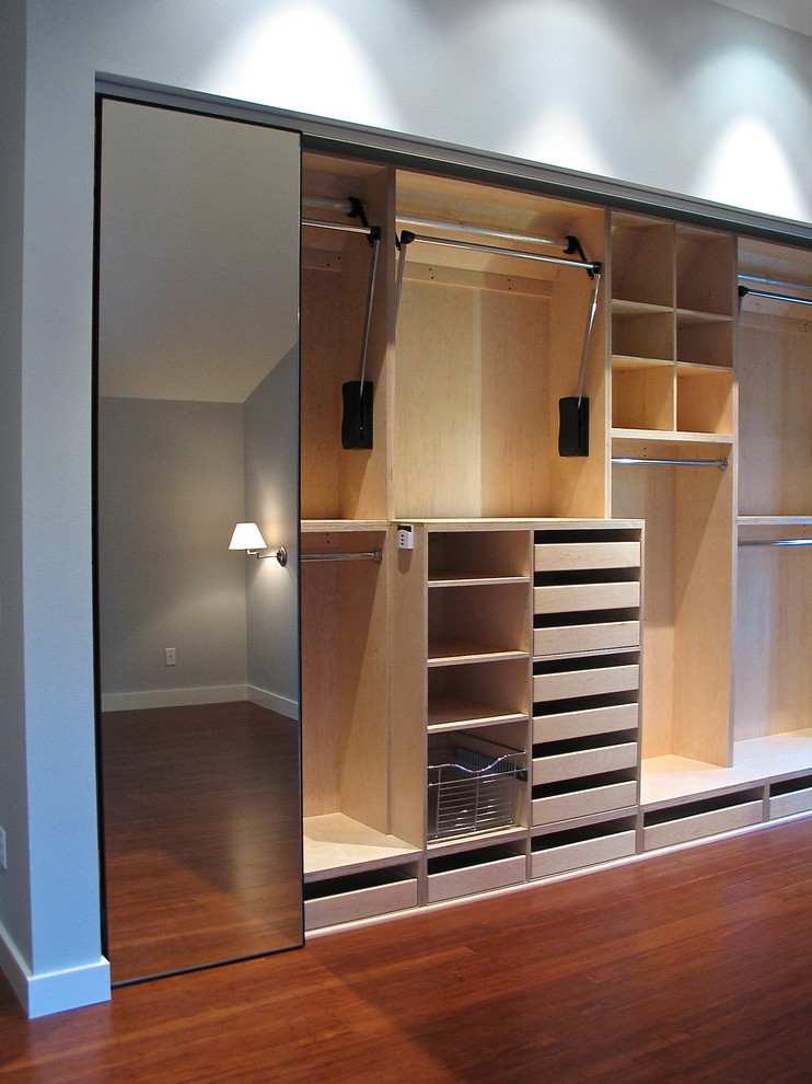 This is an example of a small modern gender-neutral built-in wardrobe in Portland with open cabinets, light wood cabinets and dark hardwood floors.