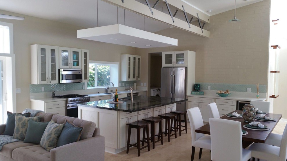 Example of a mid-sized transitional single-wall beige floor open concept kitchen design in Hawaii with an undermount sink, shaker cabinets, white cabinets, blue backsplash, glass tile backsplash, stainless steel appliances, an island and brown countertops