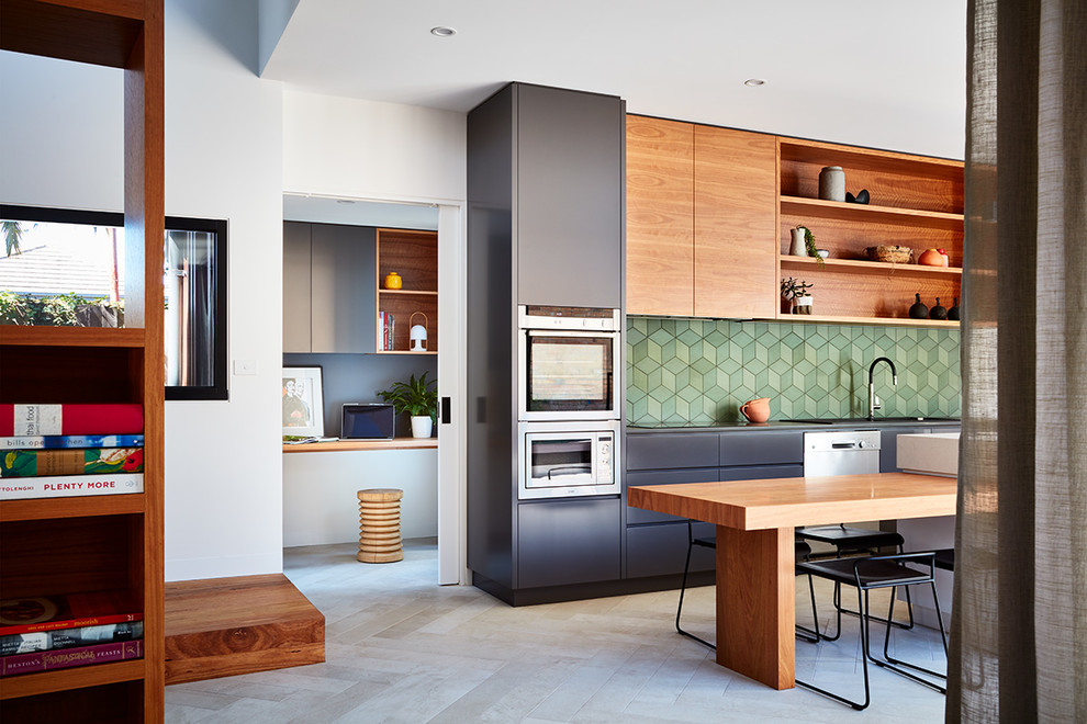 Inspiration for a contemporary galley eat-in kitchen in Melbourne with a double-bowl sink, flat-panel cabinets, black cabinets, solid surface benchtops, green splashback, porcelain splashback, stainless steel appliances, porcelain floors and with island.