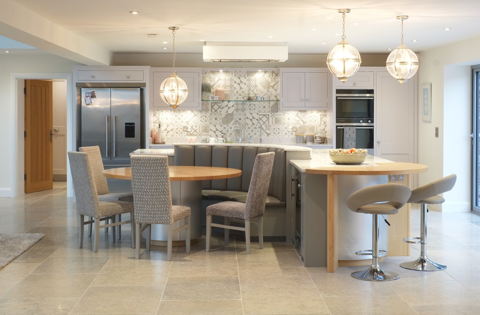 Photo of a large transitional single-wall eat-in kitchen in Other with shaker cabinets, white cabinets, quartzite benchtops, grey splashback, stainless steel appliances, limestone floors, with island and beige floor.