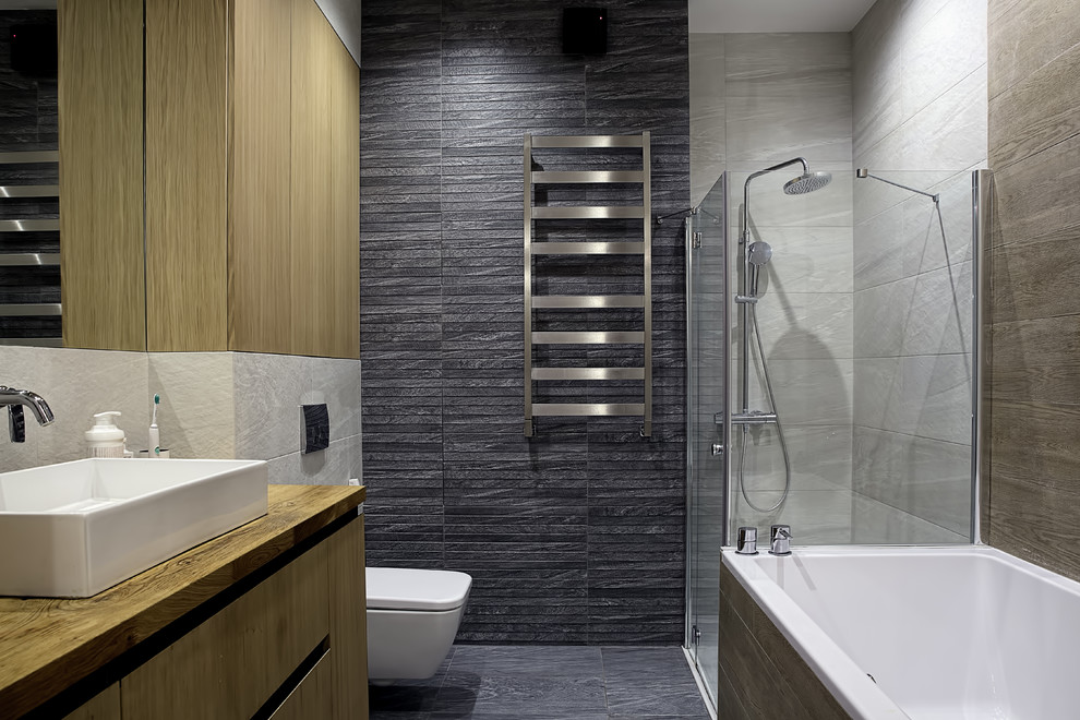 Inspiration for a mid-sized contemporary master bathroom in Moscow with flat-panel cabinets, medium wood cabinets, an alcove shower, a wall-mount toilet, gray tile, porcelain tile, porcelain floors, a vessel sink, wood benchtops and a drop-in tub.