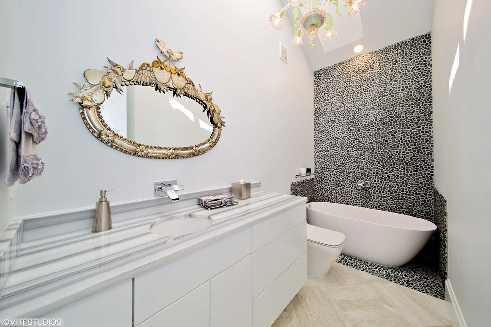 Design ideas for a modern bathroom in Miami with flat-panel cabinets, white cabinets, marble benchtops, a freestanding tub, pebble tile, grey walls and porcelain floors.