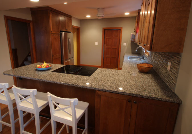 Example of a mid-sized transitional l-shaped light wood floor eat-in kitchen design with an undermount sink, shaker cabinets, dark wood cabinets, granite countertops, multicolored backsplash, mosaic tile backsplash, stainless steel appliances and a peninsula