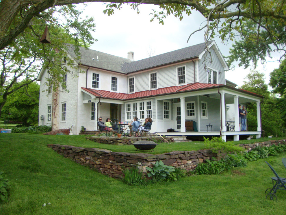 Cette photo montre une façade de maison blanche nature en panneau de béton fibré et bardage à clin de taille moyenne et à un étage avec un toit à deux pans, un toit mixte et un toit rouge.