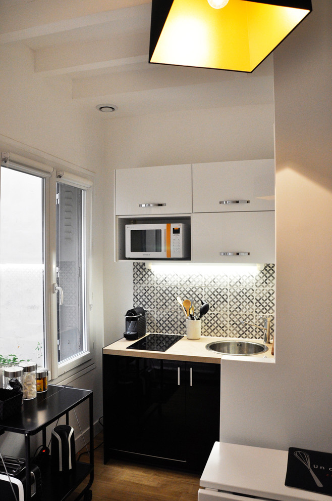 Photo of a mid-sized contemporary l-shaped separate kitchen in Paris with black cabinets and no island.
