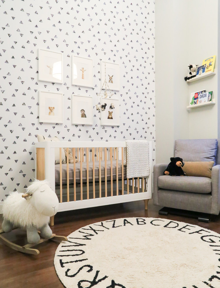 Photo of a small contemporary gender-neutral nursery in New York with grey walls, dark hardwood floors and brown floor.