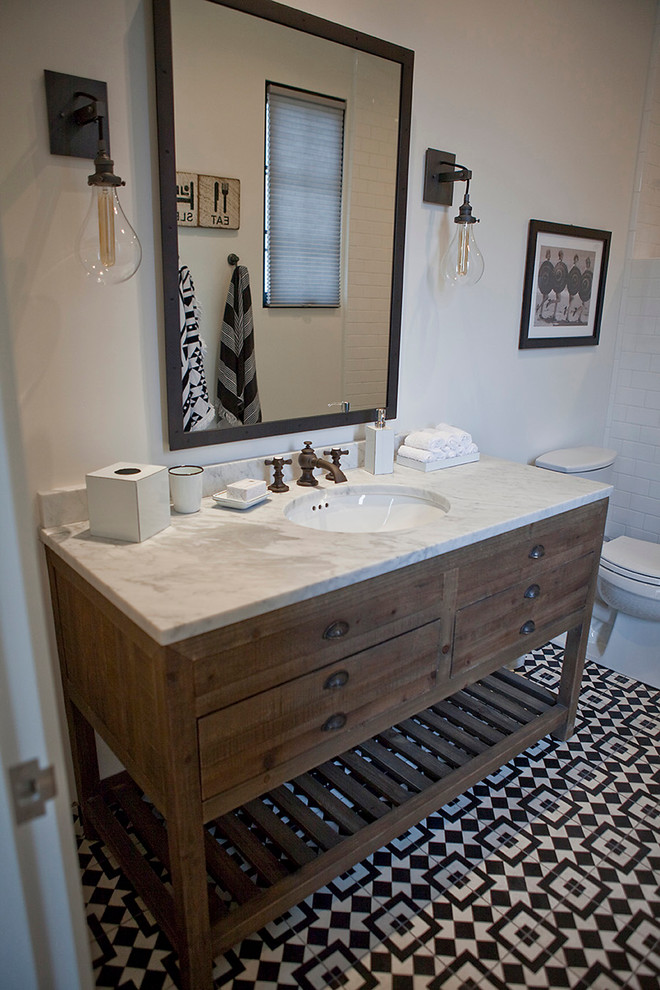 Photo of a mid-sized transitional bathroom in San Diego with medium wood cabinets, an alcove shower, a one-piece toilet, black and white tile, cement tile, white walls, ceramic floors, an undermount sink, marble benchtops and furniture-like cabinets.