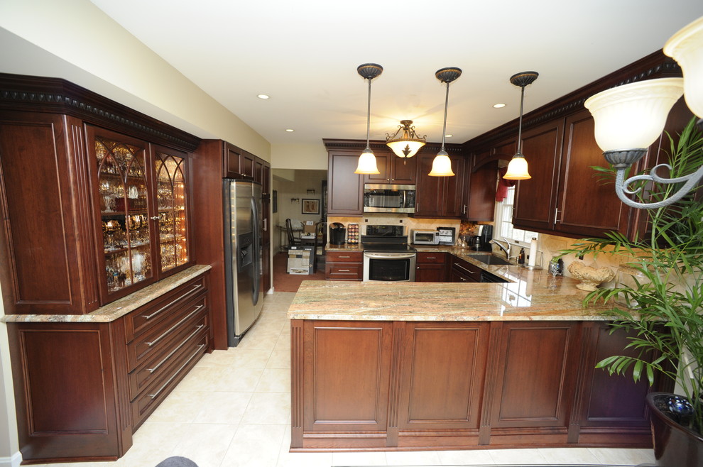 Enclosed kitchen - mid-sized transitional u-shaped limestone floor enclosed kitchen idea in Baltimore with an undermount sink, beaded inset cabinets, dark wood cabinets, granite countertops, beige backsplash, stone tile backsplash, stainless steel appliances and a peninsula