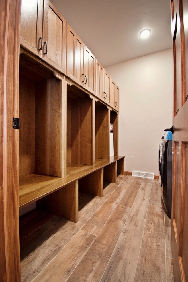 Photo of a large country u-shaped utility room in Other with an utility sink, recessed-panel cabinets, medium wood cabinets, laminate benchtops, white walls, medium hardwood floors, a side-by-side washer and dryer, brown floor and brown benchtop.