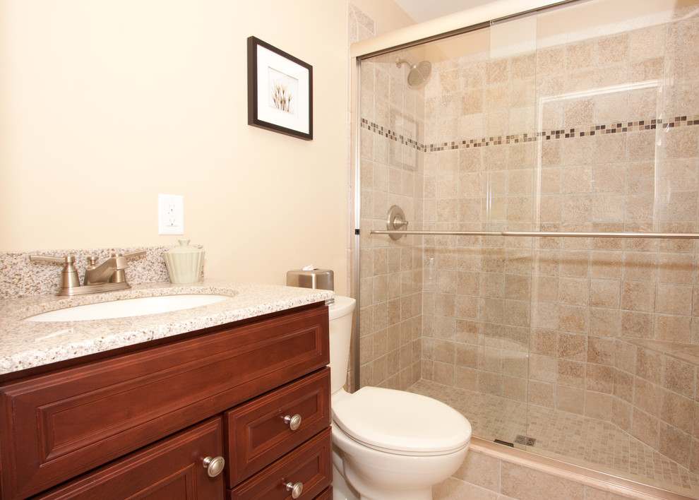 Photo of a traditional powder room in New York with an undermount sink, recessed-panel cabinets, dark wood cabinets, granite benchtops, a two-piece toilet, beige tile, porcelain tile, beige walls and porcelain floors.