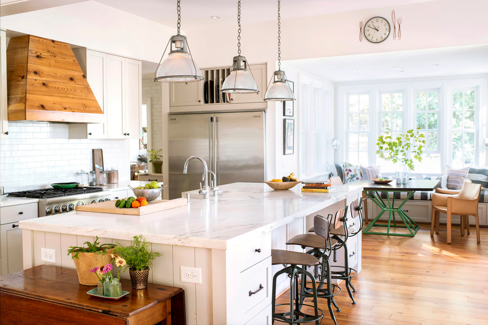 This is an example of a traditional eat-in kitchen in Raleigh with shaker cabinets, grey cabinets, white splashback, subway tile splashback, stainless steel appliances, medium hardwood floors, with island, marble benchtops and beige floor.