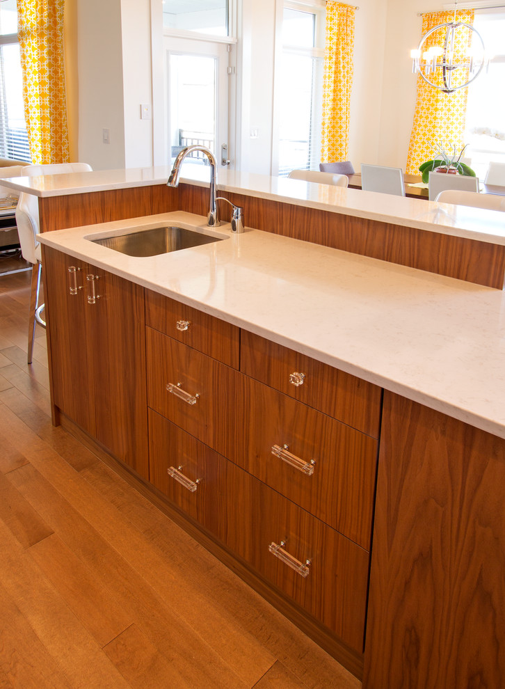Example of a large minimalist l-shaped medium tone wood floor eat-in kitchen design with an undermount sink, flat-panel cabinets, medium tone wood cabinets, quartz countertops, white backsplash, ceramic backsplash, stainless steel appliances and an island