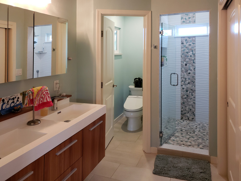 Example of a mid-sized transitional 3/4 white tile and porcelain tile porcelain tile, beige floor and double-sink alcove shower design with flat-panel cabinets, medium tone wood cabinets, a two-piece toilet, blue walls, an integrated sink, quartz countertops, a hinged shower door, white countertops, a niche and a floating vanity