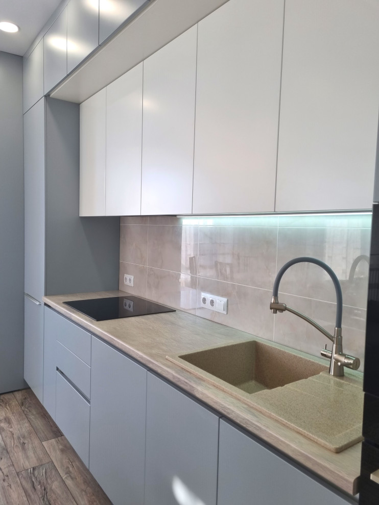 This is an example of a mid-sized transitional single-wall open plan kitchen in Other with a drop-in sink, turquoise cabinets, beige splashback, porcelain splashback, panelled appliances and beige benchtop.