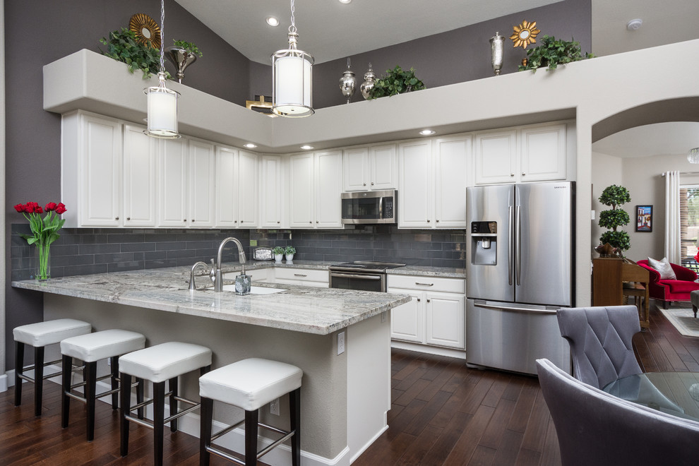 Mid-sized transitional u-shaped dark wood floor eat-in kitchen photo in Phoenix with an undermount sink, raised-panel cabinets, white cabinets, granite countertops, gray backsplash, glass tile backsplash, stainless steel appliances and a peninsula