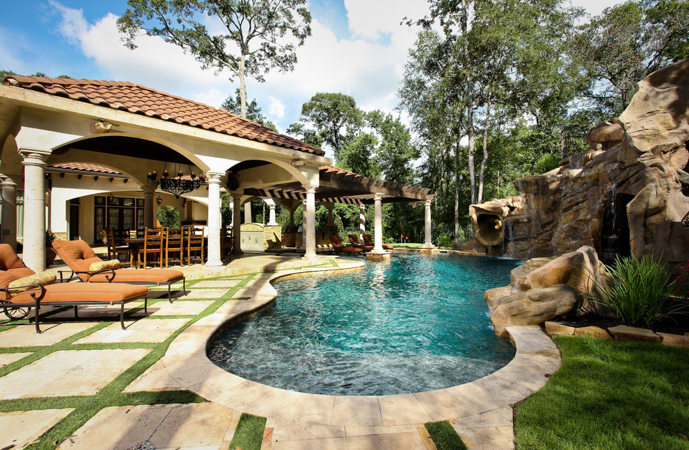This is an example of a mediterranean backyard custom-shaped natural pool in Houston with a water slide.