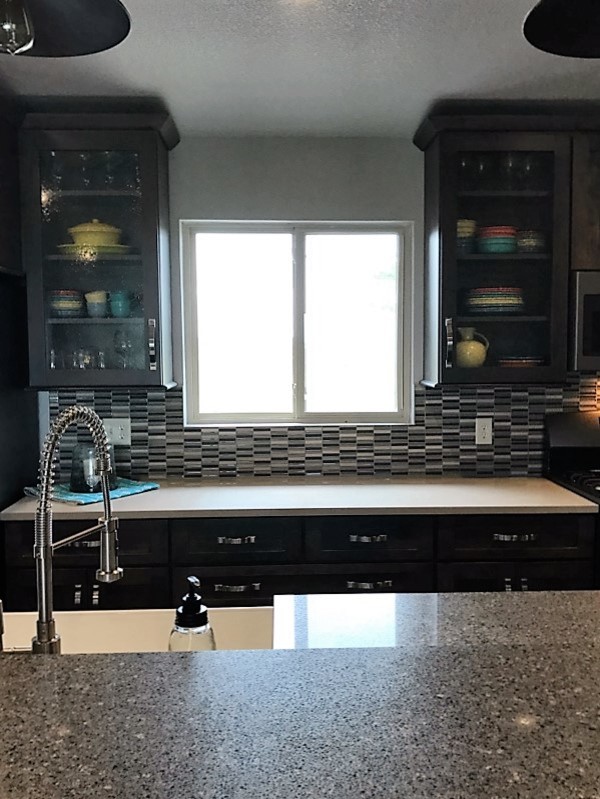 Open concept kitchen - mid-sized transitional single-wall light wood floor open concept kitchen idea with shaker cabinets, dark wood cabinets, multicolored backsplash, glass tile backsplash, stainless steel appliances, an island, a farmhouse sink and granite countertops