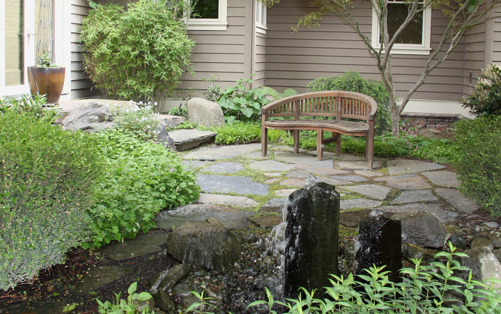 This is an example of a mid-sized arts and crafts side yard shaded garden in Seattle with a water feature and natural stone pavers.