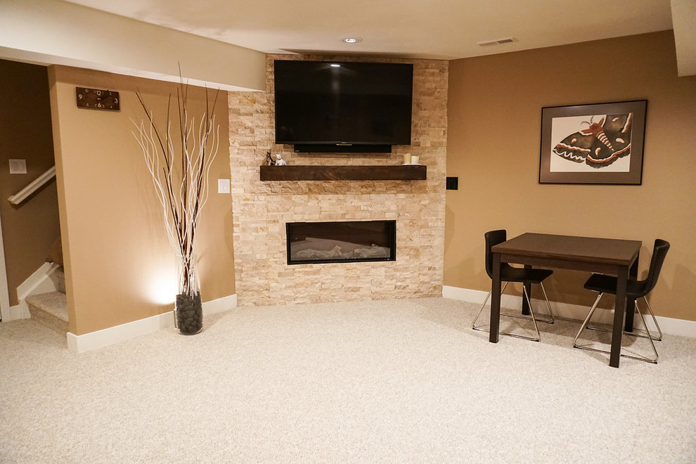This is an example of a mid-sized contemporary fully buried basement in Denver with beige walls, carpet, a corner fireplace, a stone fireplace surround and beige floor.