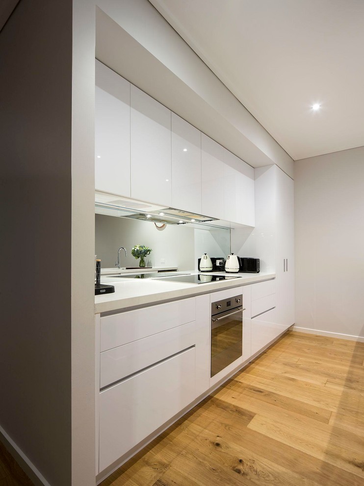 Contemporary kitchen in Melbourne with a double-bowl sink, white cabinets, granite benchtops, multi-coloured splashback, mirror splashback, stainless steel appliances and light hardwood floors.