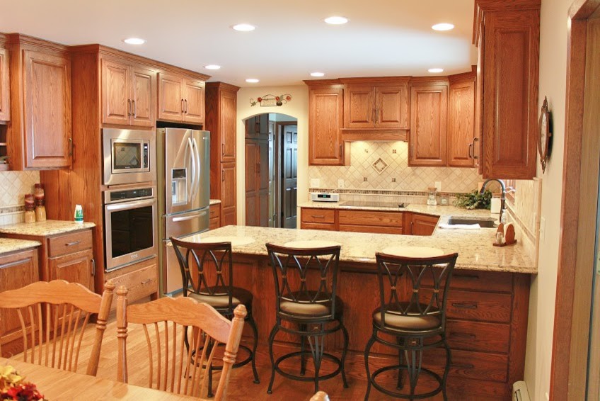Mid-sized minimalist u-shaped light wood floor eat-in kitchen photo with an undermount sink, raised-panel cabinets, medium tone wood cabinets, quartz countertops, multicolored backsplash, ceramic backsplash, stainless steel appliances and an island