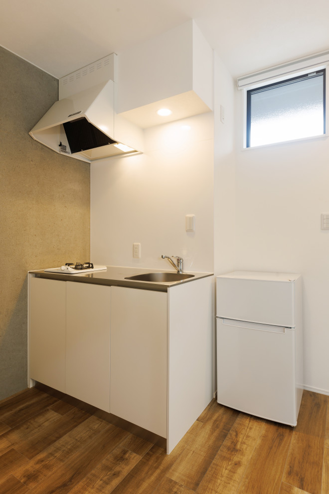 Inspiration for a small modern single-wall open plan kitchen in Other with a single-bowl sink, white cabinets, stainless steel worktops, white splashback, white appliances, plywood flooring, brown floors and a wallpapered ceiling.