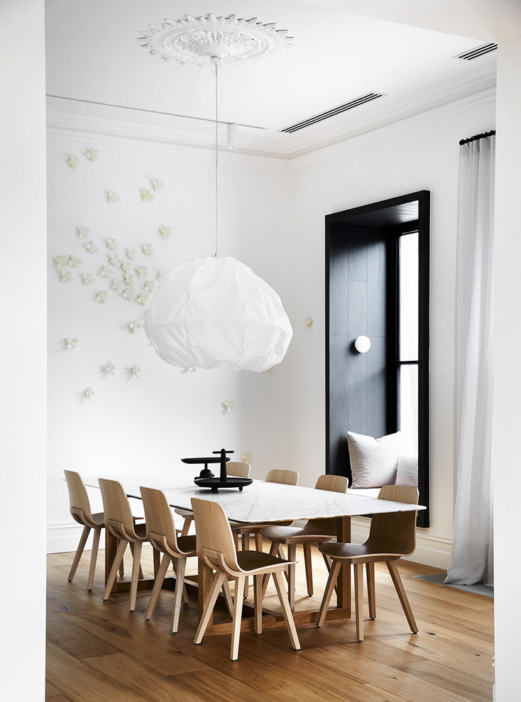 Inspiration for a scandinavian separate dining room in Melbourne with white walls, medium hardwood floors and brown floor.