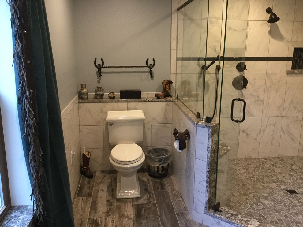 Example of a large mountain style master gray tile and porcelain tile porcelain tile corner shower design with beaded inset cabinets, dark wood cabinets, a two-piece toilet, gray walls, an undermount sink and granite countertops