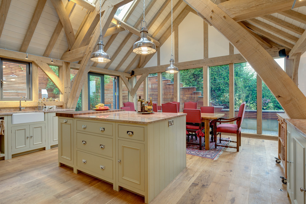This is an example of a traditional u-shaped eat-in kitchen in Devon with a farmhouse sink, recessed-panel cabinets and beige cabinets.