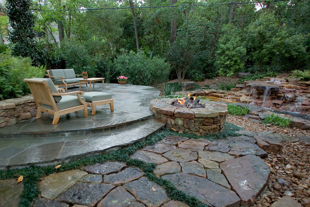Photo of a mid-sized tropical backyard patio in Houston with a fire feature and natural stone pavers.