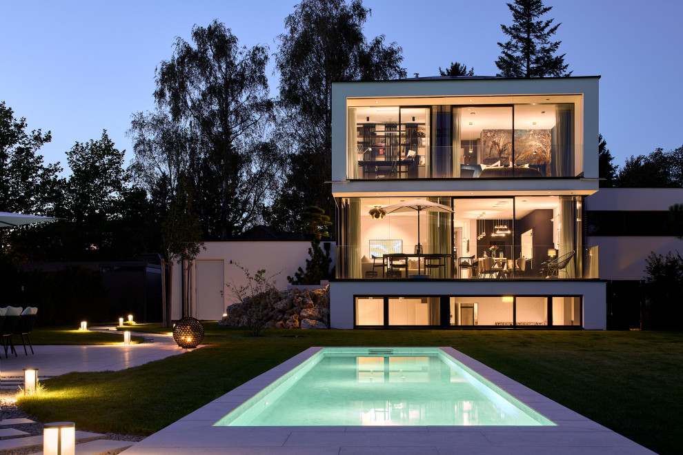Contemporary white two-story stucco exterior home idea in Munich with a hip roof, a metal roof and a black roof