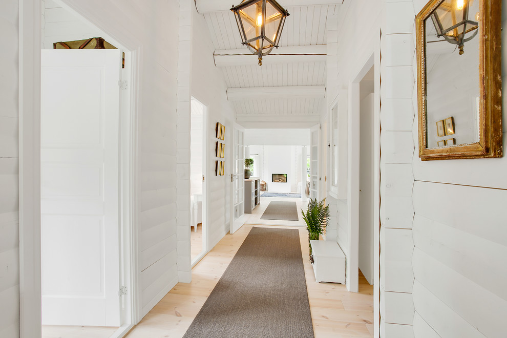 Large scandinavian hallway in Miami with white walls and light hardwood floors.