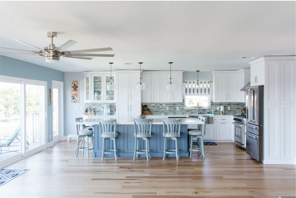 Design ideas for a mid-sized beach style l-shaped kitchen in Miami with a farmhouse sink, shaker cabinets, white cabinets, quartzite benchtops, laminate floors, with island and white benchtop.