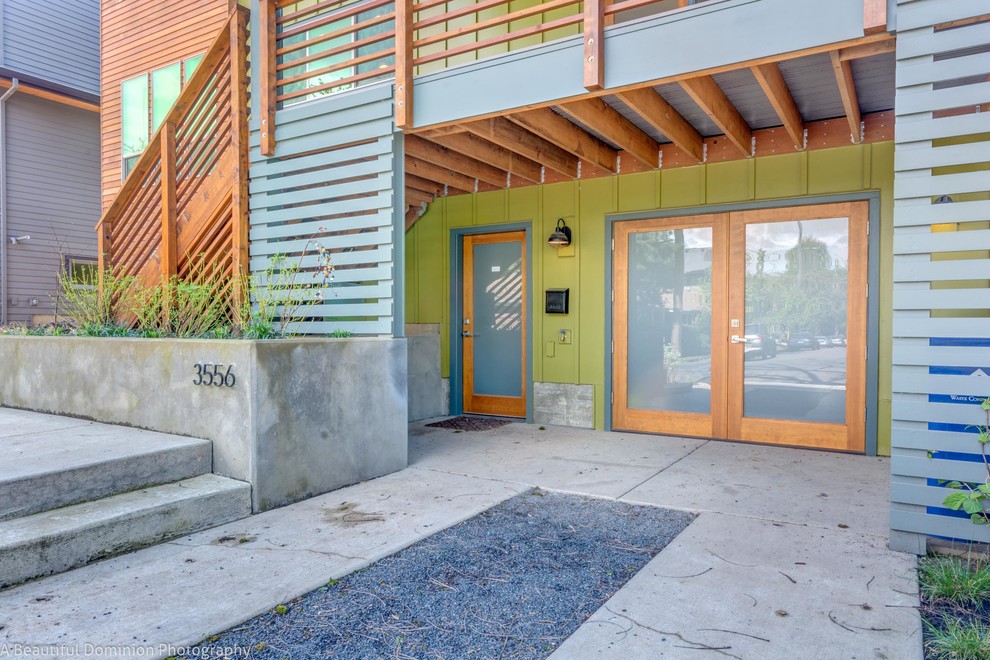 Photo of a mid-sized contemporary three-storey green exterior in Portland with wood siding.