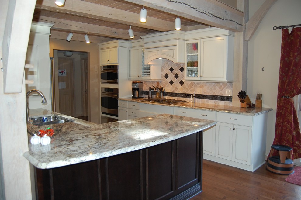Inspiration for a mid-sized transitional u-shaped medium tone wood floor open concept kitchen remodel in Chicago with an undermount sink, flat-panel cabinets, dark wood cabinets, granite countertops, beige backsplash, stone tile backsplash, stainless steel appliances and a peninsula