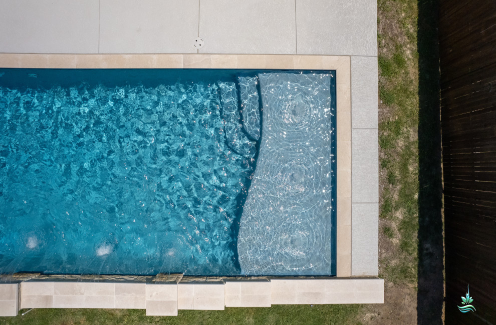 Ispirazione per una piscina monocorsia stile americano rettangolare di medie dimensioni e dietro casa con paesaggistica bordo piscina e lastre di cemento