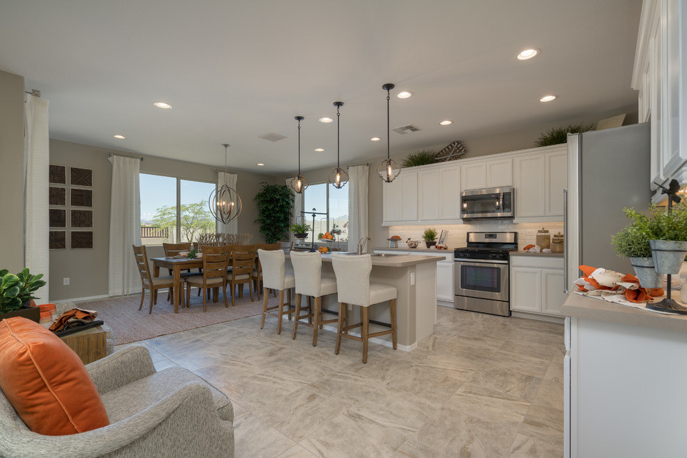 Large contemporary l-shaped eat-in kitchen in Phoenix with a double-bowl sink, raised-panel cabinets, white cabinets, solid surface benchtops, white splashback, subway tile splashback, stainless steel appliances, cement tiles, with island, beige floor and beige benchtop.