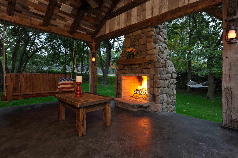 Photo of a large country backyard patio in New York with a fire feature, concrete slab and a roof extension.