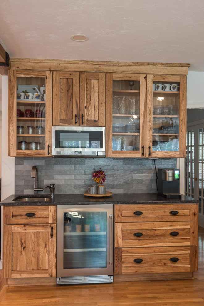 Example of a large transitional single-wall light wood floor and brown floor eat-in kitchen design in Boston with a farmhouse sink, shaker cabinets, white cabinets, granite countertops, gray backsplash, ceramic backsplash, stainless steel appliances, an island and gray countertops