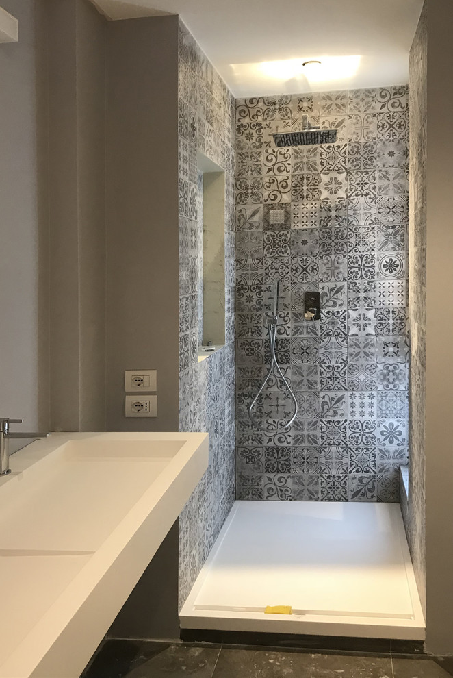 Large contemporary master bathroom in Rome with open cabinets, white cabinets, an alcove shower, a wall-mount toilet, gray tile, porcelain tile, grey walls, porcelain floors, a trough sink, grey floor and a hinged shower door.