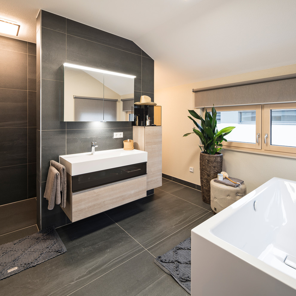 Пример оригинального дизайна: ванная комната в современном стиле с отдельно стоящей ванной, серой плиткой, бежевыми стенами и серым полом