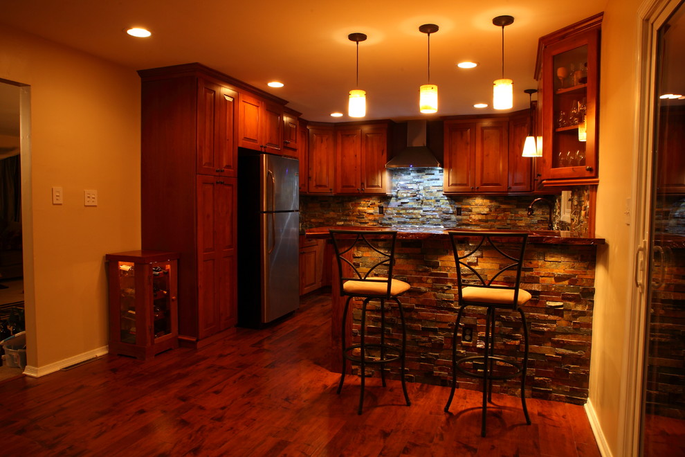 Example of a small mountain style u-shaped eat-in kitchen design with a single-bowl sink, raised-panel cabinets, medium tone wood cabinets, granite countertops, multicolored backsplash, stone slab backsplash, stainless steel appliances and no island