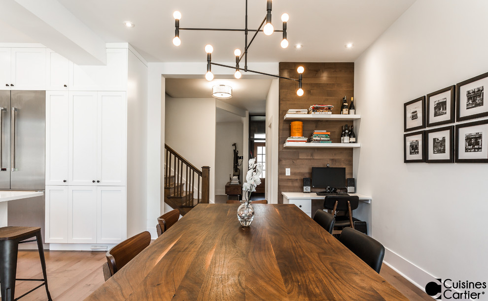 Mid-sized transitional l-shaped medium tone wood floor eat-in kitchen photo in Montreal with a farmhouse sink, shaker cabinets, white cabinets, quartzite countertops, white backsplash, mosaic tile backsplash, stainless steel appliances and an island